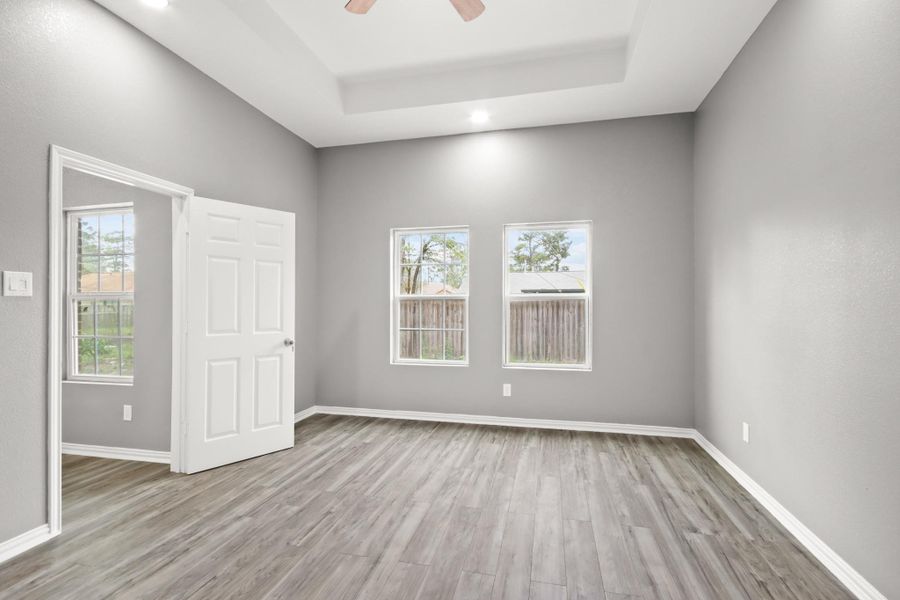 Primary bedroom features an inlet ceiling, lots of natural light, and a ceiling fan.