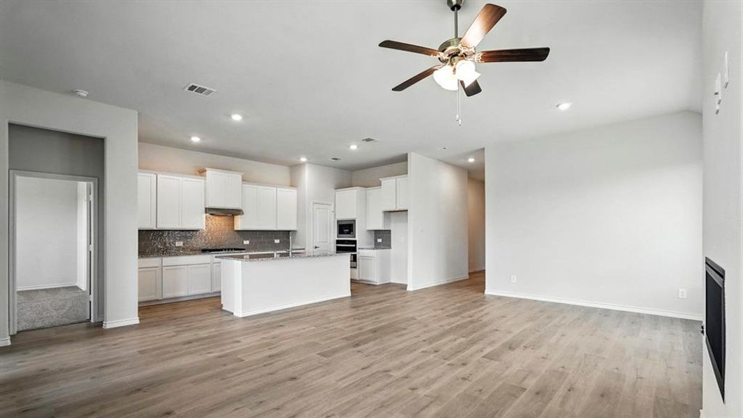 Open-concept living space featuring wood-finish flooring, recessed lighting, and a modern ceiling fan Open-concept living space featuring wood-finish flooring, recessed lighting, and a modern ceiling fan