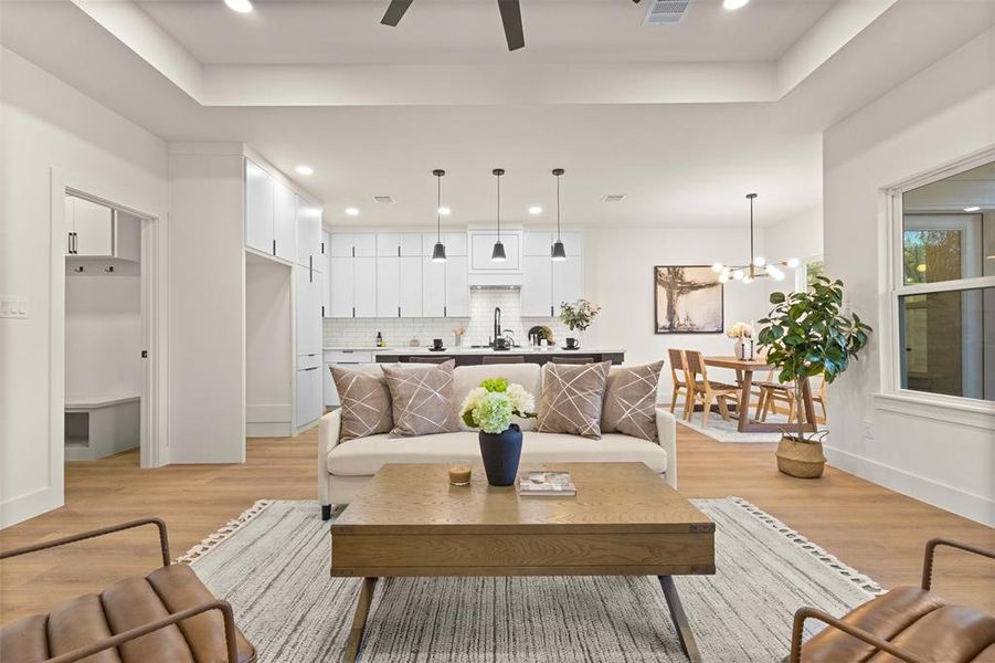Living room with light wood finished floors, recessed lighting, ceiling fan, and a chandelier