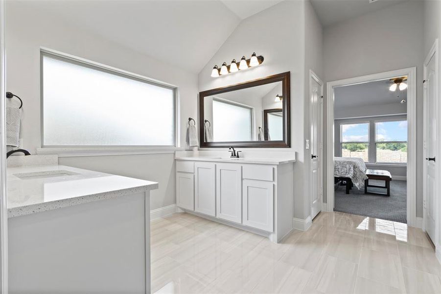 Bathroom with tile patterned floors, vaulted ceiling, and vanity