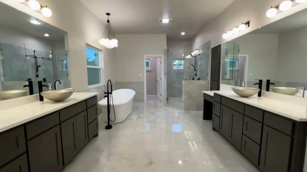 Bathroom with two vanities, a marble finish shower, a soaking tub, and light marble finish floors