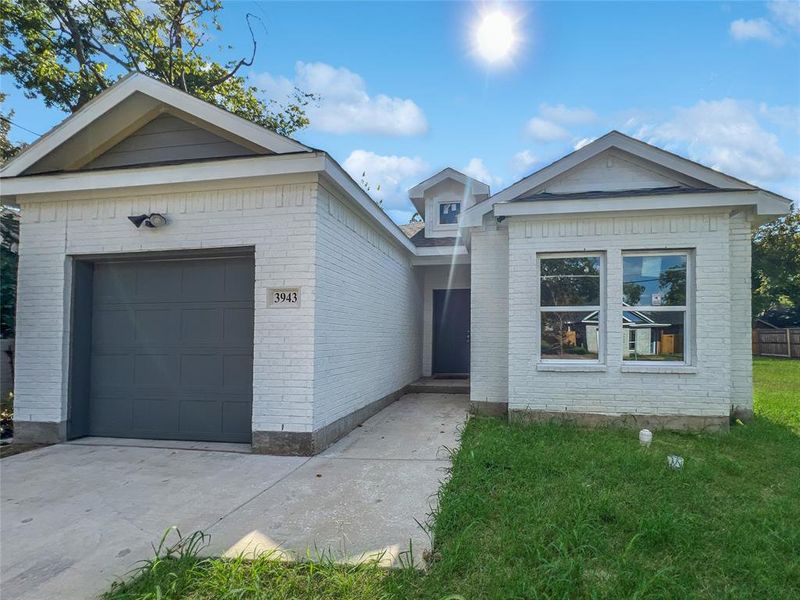 Ranch-style house featuring a garage and a front lawn