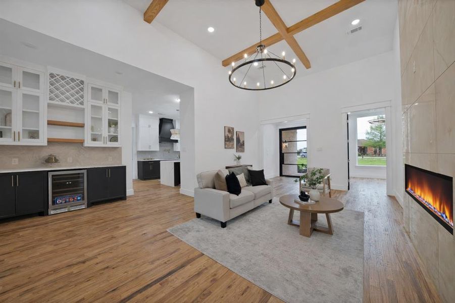 Spacious living area featuring high vaulted ceilings with exposed beams, a modern chandelier, and warm hardwood flooring