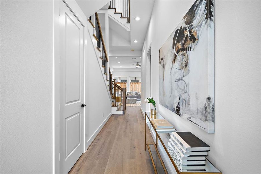 Previously built by Riverway Homes finishes will be similar.This photo showcases a modern, bright hallway with wood flooring, leading to a living area.