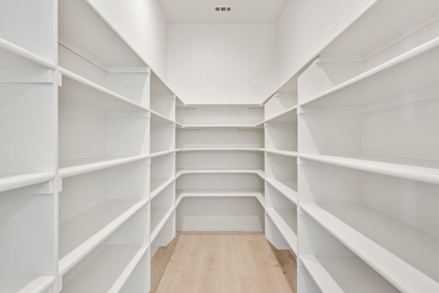 Walk-in pantry or closet with white wrap-around shelving on three walls and light wood floors Walk-in pantry or closet with white wrap-around shelving on three walls and light wood floors