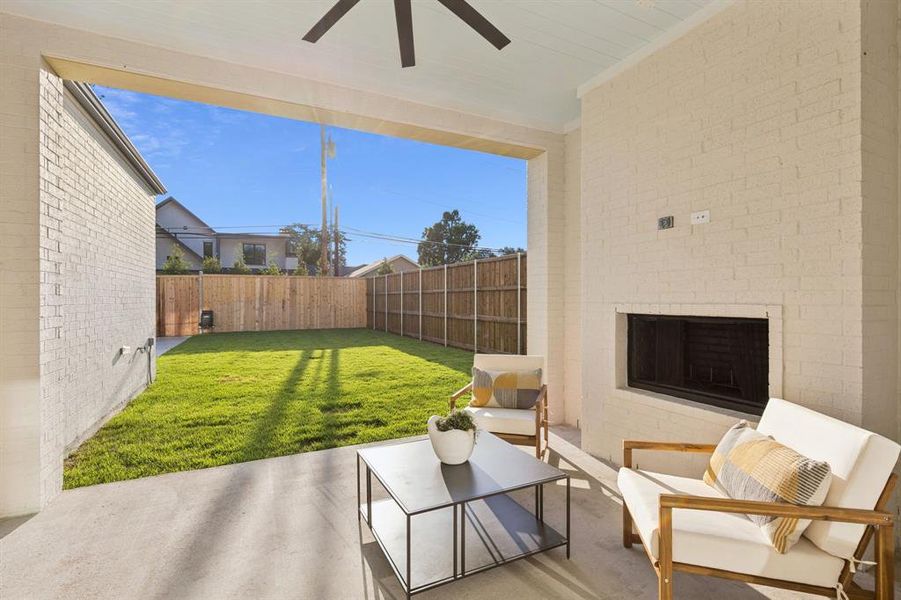Fenced backyard featuring an outdoor brick fireplace, a patio, and ceiling fan