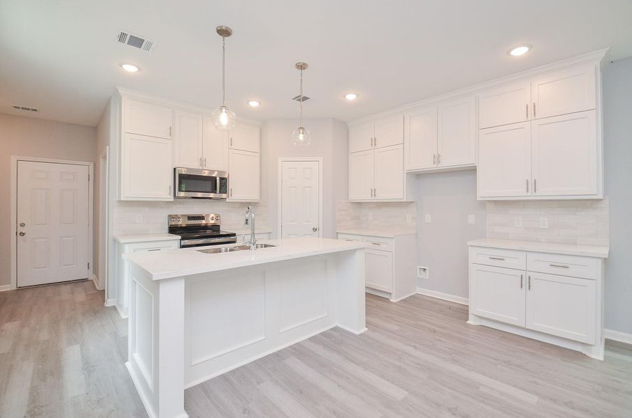 Crisp finishes, quality hardware, and a sleek backsplash elevate the look without sacrificing function.