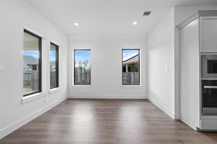 The breakfast room is filled with natural light and features high ceilings, recessed lighting, and expansive windows.
