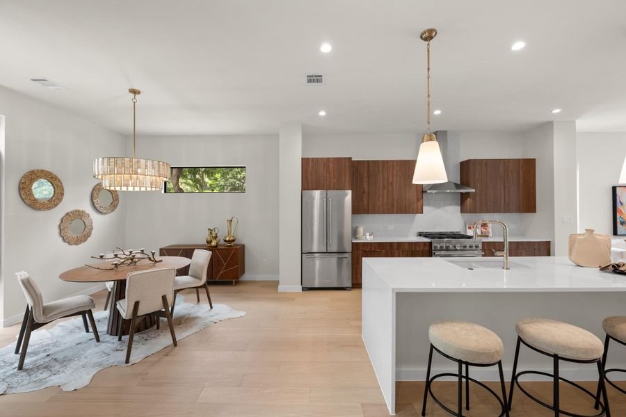 Blonde wood flooring unifies the open-concept dining area and sleek modern kitchen. Blonde wood flooring unifies the open-concept dining area and sleek modern kitchen.