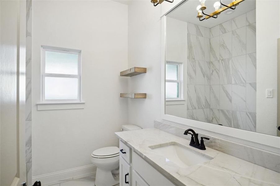 Bathroom featuring a chandelier, vanity, and toilet