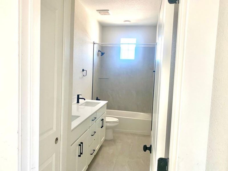 Bathroom featuring shower / washtub combination, double vanity, and a textured ceiling Bathroom featuring shower / washtub combination, double vanity, and a textured ceiling