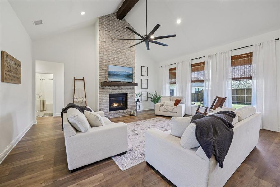 Living room featuring a brick fireplace, dark wood-type flooring, recessed lighting, high vaulted ceiling, and beamed ceiling Living room featuring a brick fireplace, dark wood-type flooring, recessed lighting, high vaulted ceiling, and beamed ceiling
