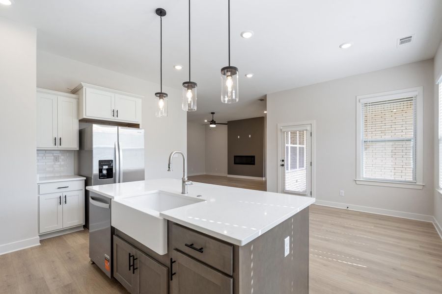 Open-concept kitchen featuring an island with a farmhouse sink and pendant lighting Open-concept kitchen featuring an island with a farmhouse sink and pendant lighting