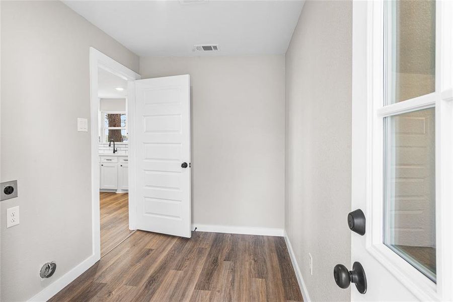 Washroom with hookup for an electric dryer and dark wood-style flooring