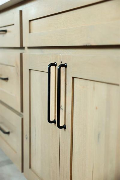 Light wood-finish cabinetry featuring shaker-style doors and drawers with matte black hardware