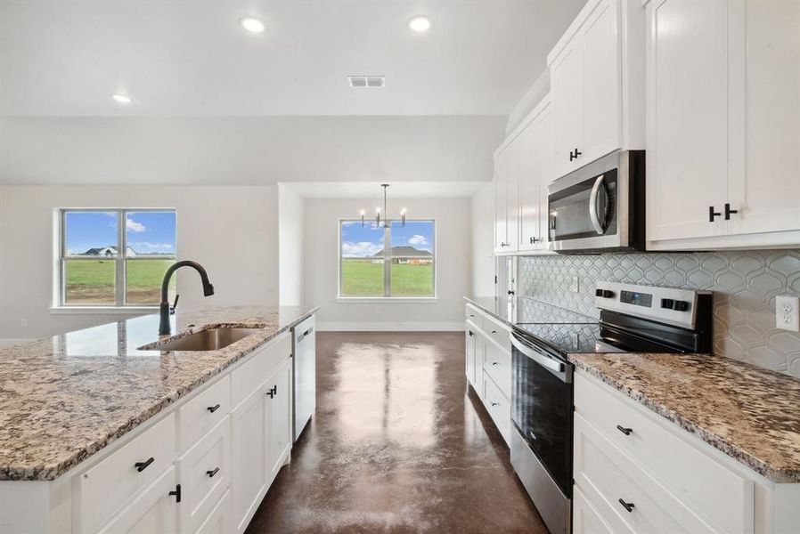 Kitchen featuring a kitchen island with sink, appliances with stainless steel finishes, decorative backsplash, pendant lighting, and sink