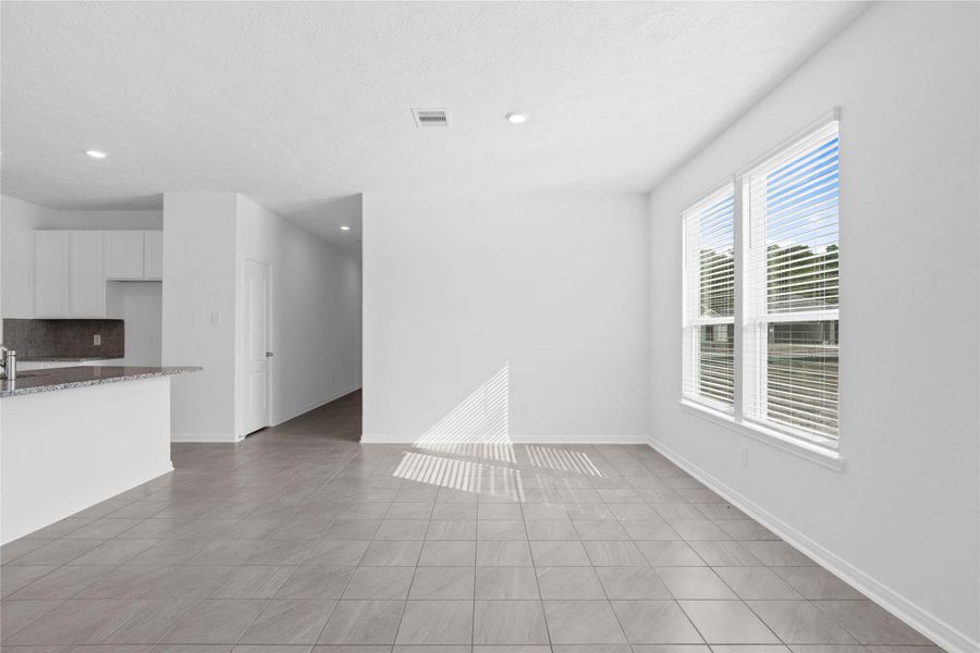 Start your day with a warm cup of coffee and quality time in this charming dining area! Highlights include large windows with blinds, custom neutral paint, tile flooring, and high ceilings with recessed lighting.