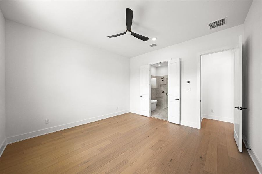 Unfurnished bedroom featuring light wood finished floors, ceiling fan, and ensuite bathroom