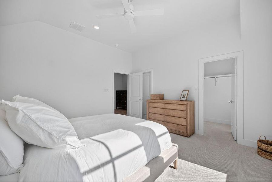 Bedroom with carpet floors, a spacious closet, a ceiling fan, and vaulted ceiling Bedroom with carpet floors, a spacious closet, a ceiling fan, and vaulted ceiling