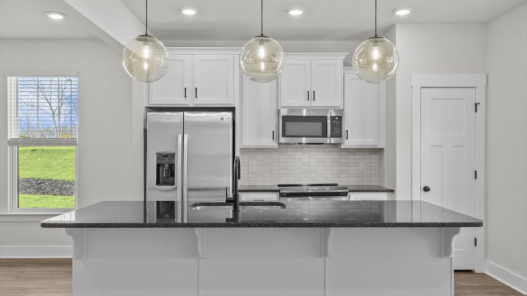 Highly skilled kitchen design includes a 9-foot island, quartz countertops, and stylish pendant fixtures