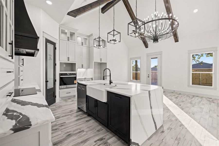 Kitchen featuring dark cabinets, white cabinetry, glass insert cabinets, an island with sink, and high vaulted ceiling Kitchen featuring dark cabinets, white cabinetry, glass insert cabinets, an island with sink, and high vaulted ceiling