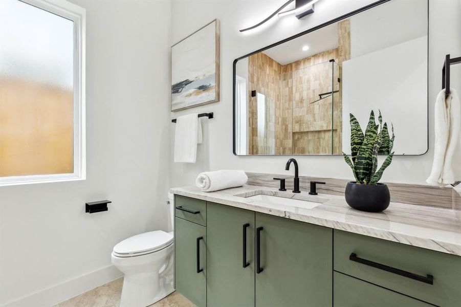 Bathroom featuring vanity, toilet, and a shower