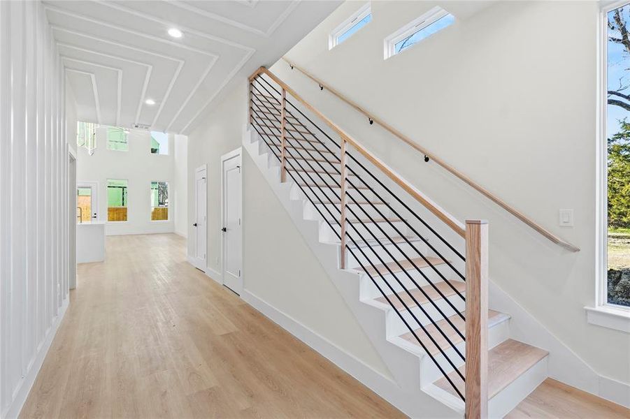 Stairs with a high ceiling, baseboards, wood finished floors, and recessed lighting