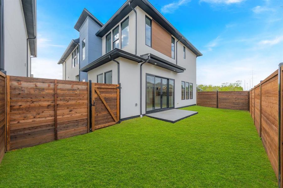 Rear view of house featuring a gate, a fenced backyard, and stucco siding