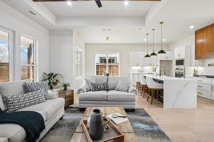 Living area featuring light wood-style flooring, recessed lighting, a ceiling fan, and a raised ceiling