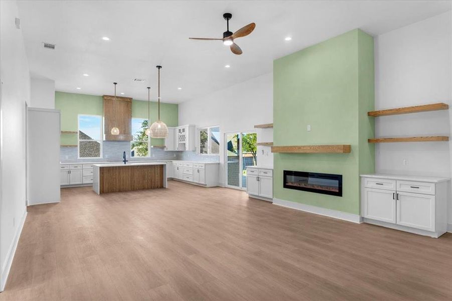 Kitchen with a center island, white cabinetry, pendant lighting, ceiling fan, and light hardwood / wood-style flooring