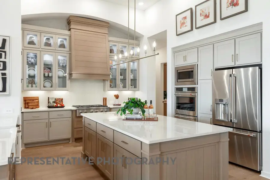 Kitchen featuring a kitchen island, appliances with stainless steel finishes, gray cabinets, and light wood finished floors
