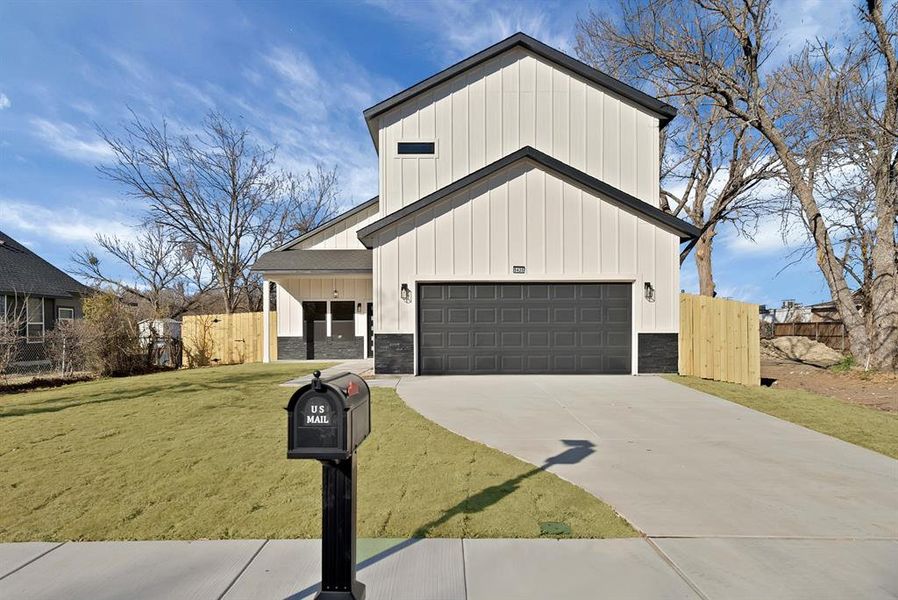Modern farmhouse style home featuring board and batten siding, stone siding, concrete driveway, and a garage