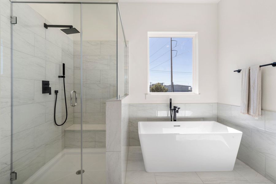 A closer look at the grand soaking bathtub with standing tub filler and sprayer, semi-frameless walk-in shower with a rain shower head.