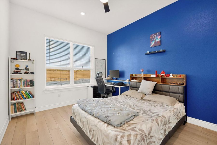 Bedroom featuring light wood finished floors, a ceiling fan, and an office area