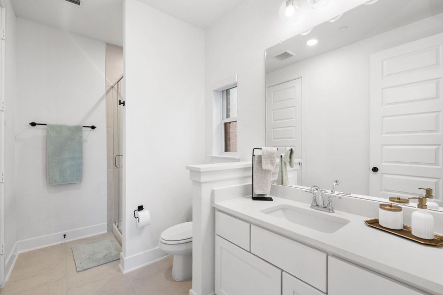 Modern bathroom featuring a single vanity with an integrated sink, a large wall-mounted mirror, and an enclosed shower with a glass door Modern bathroom featuring a single vanity with an integrated sink, a large wall-mounted mirror, and an enclosed shower with a glass door