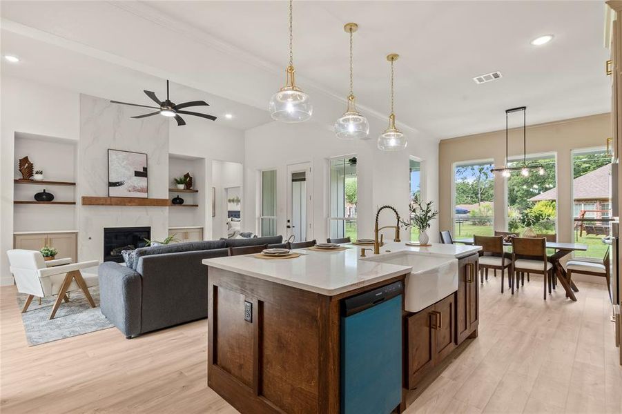 Kitchen featuring a sink, dishwashing machine, built in features, light countertops, and light wood-style floors Kitchen featuring a sink, dishwashing machine, built in features, light countertops, and light wood-style floors
