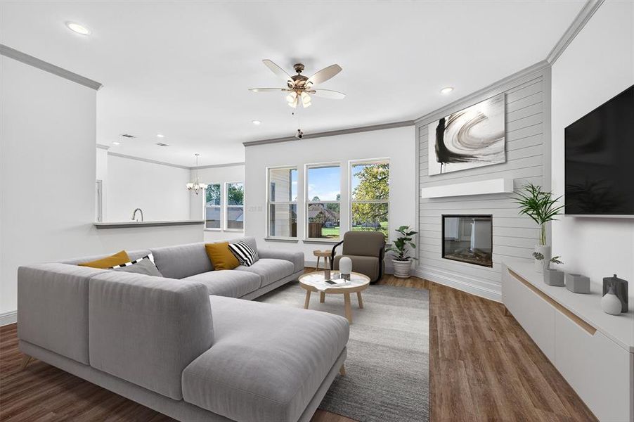 Living room featuring ornamental molding, a fireplace, wood finished floors, a ceiling fan, and a chandelier