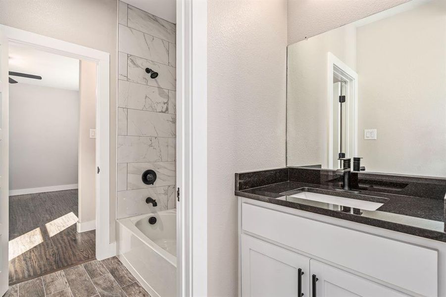 Bathroom with tiled shower / bath, vanity, and hardwood / wood-style flooring