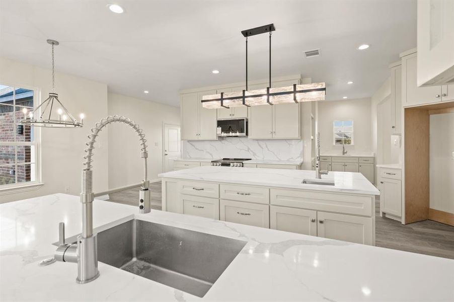 Kitchen featuring white cabinets, hanging light fixtures, light stone countertops, dark wood-type flooring, and recessed lighting Kitchen featuring white cabinets, hanging light fixtures, light stone countertops, dark wood-type flooring, and recessed lighting