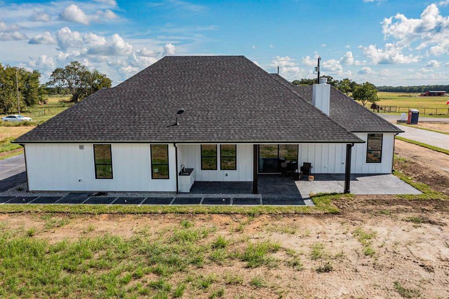 Back of property featuring a rural view and a patio area