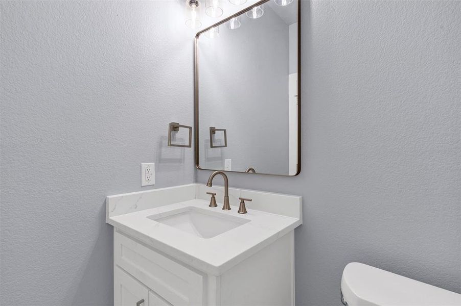 Half bath with vanity and a textured wall