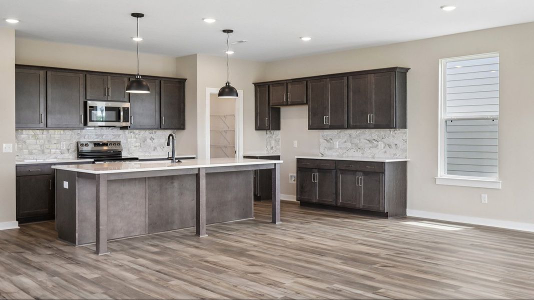 Kitchen with dark cabinetry, quartz countertops, and tile backsplash