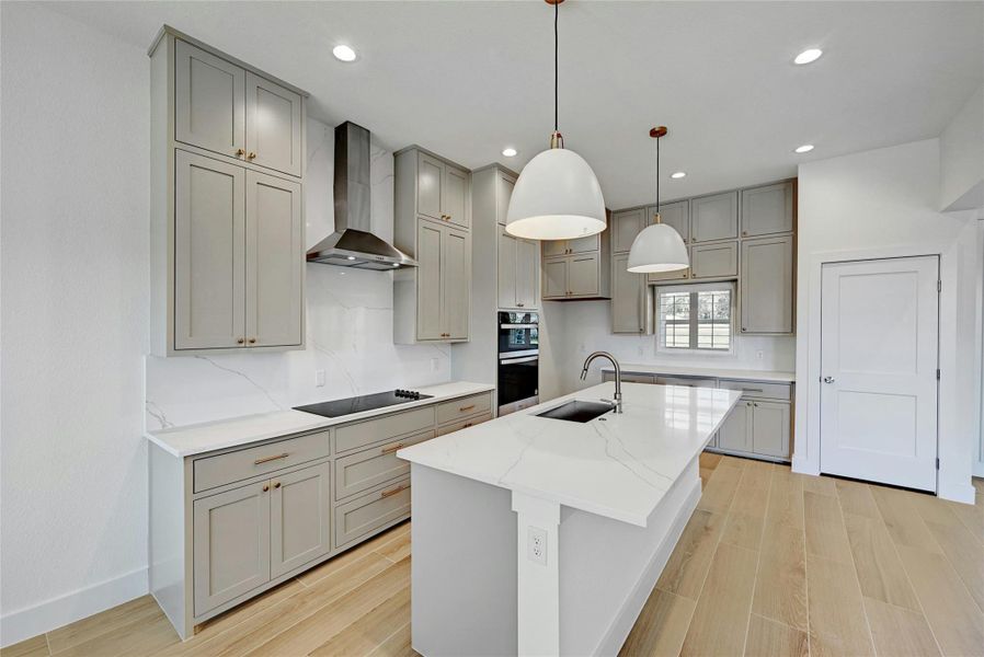 This kitchen offers beautiful pedant lighting, large kitchen island, stainless steel appliances, and plenty of custom cabinetry!