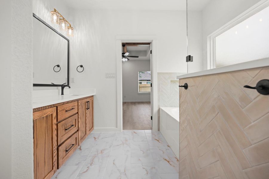 A well-appointed primary bathroom showcases a double vanity, a modern soaking tub, and stylish tile work. A well-appointed primary bathroom showcases a double vanity, a modern soaking tub, and stylish tile work.
