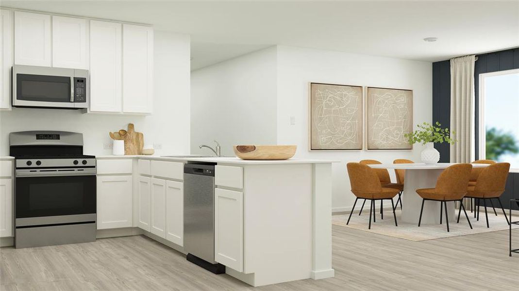 Kitchen featuring stainless steel appliances, light countertops, a peninsula, light wood-style flooring, and white cabinets