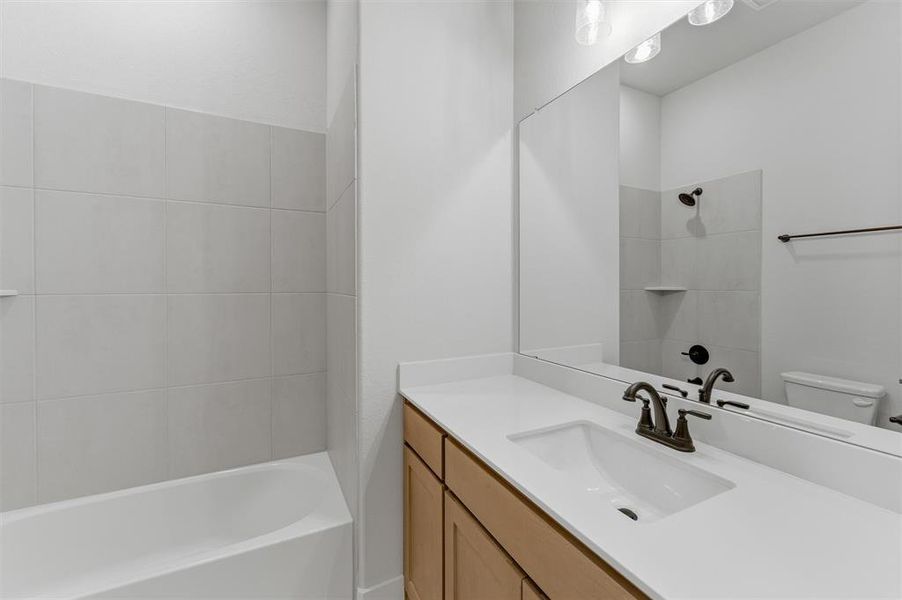 Bathroom vanity featuring an integrated sink, broad countertop, and wood-finish cabinetry