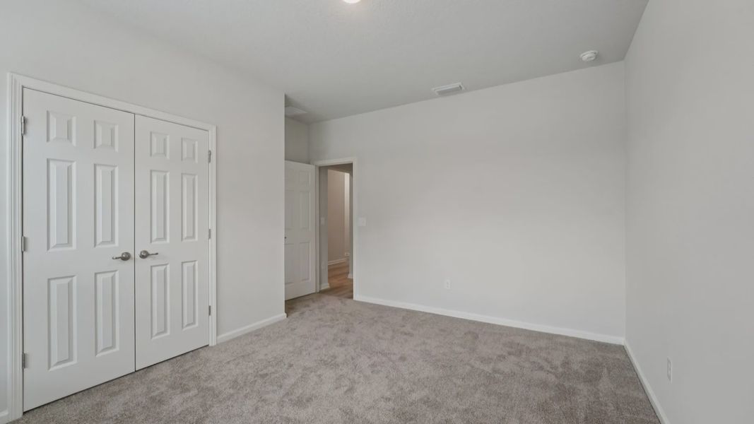 Experience tranquility in this carpeted bedroom featuring neutral tones and refined details in Palm Coast.