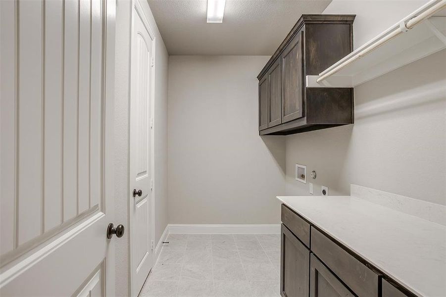 Laundry room with cabinets, hookup for an electric dryer, light tile patterned flooring, and washer hookup