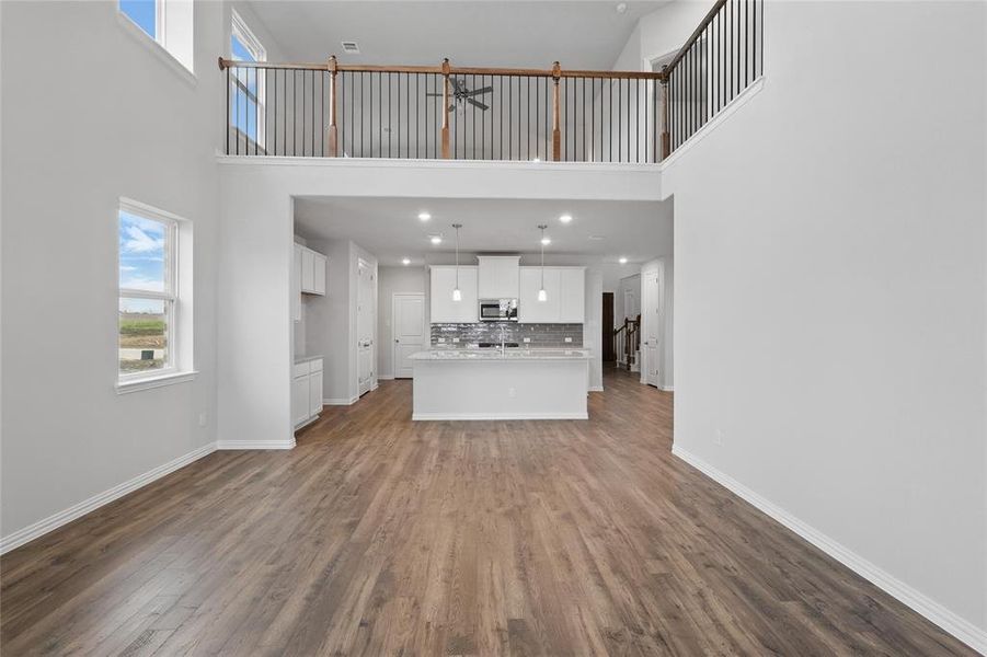 Unfurnished living room featuring a high ceiling, dark wood-style flooring, and ceiling fan