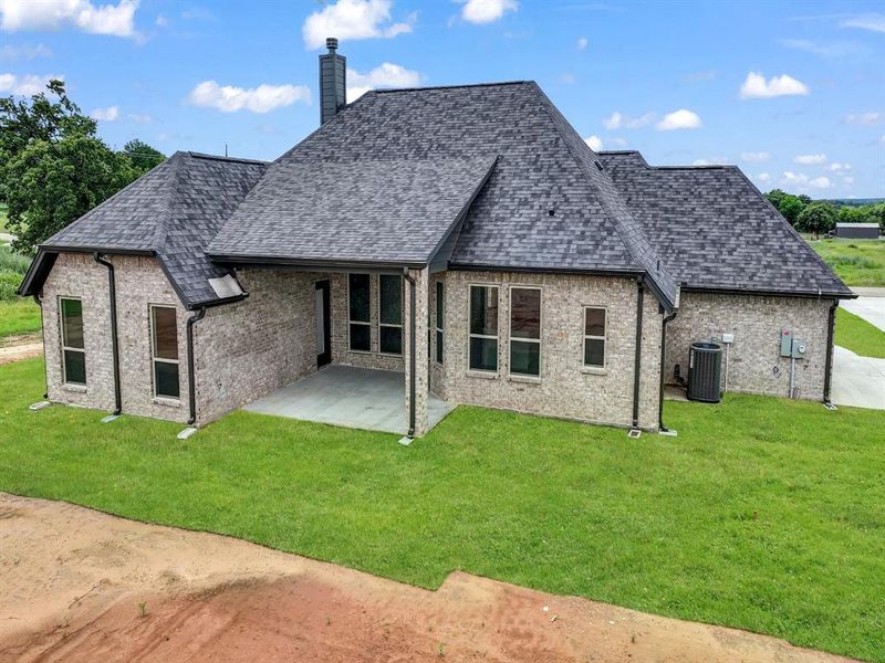 Rear view of property with a patio area, brick siding, a yard, and a chimney